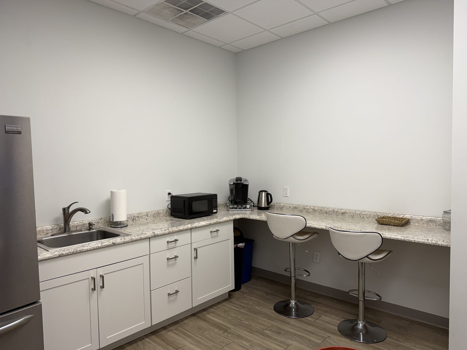 Modern break room with refrigerator, microwave, coffee maker, and seating