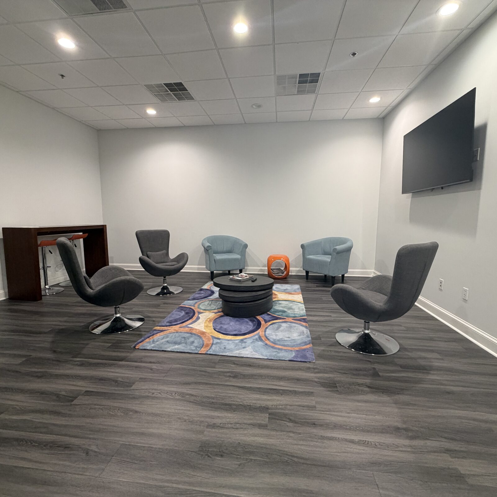 Business Lounge with swivel chairs around a coffee table, mounted display, and modern lounge seating